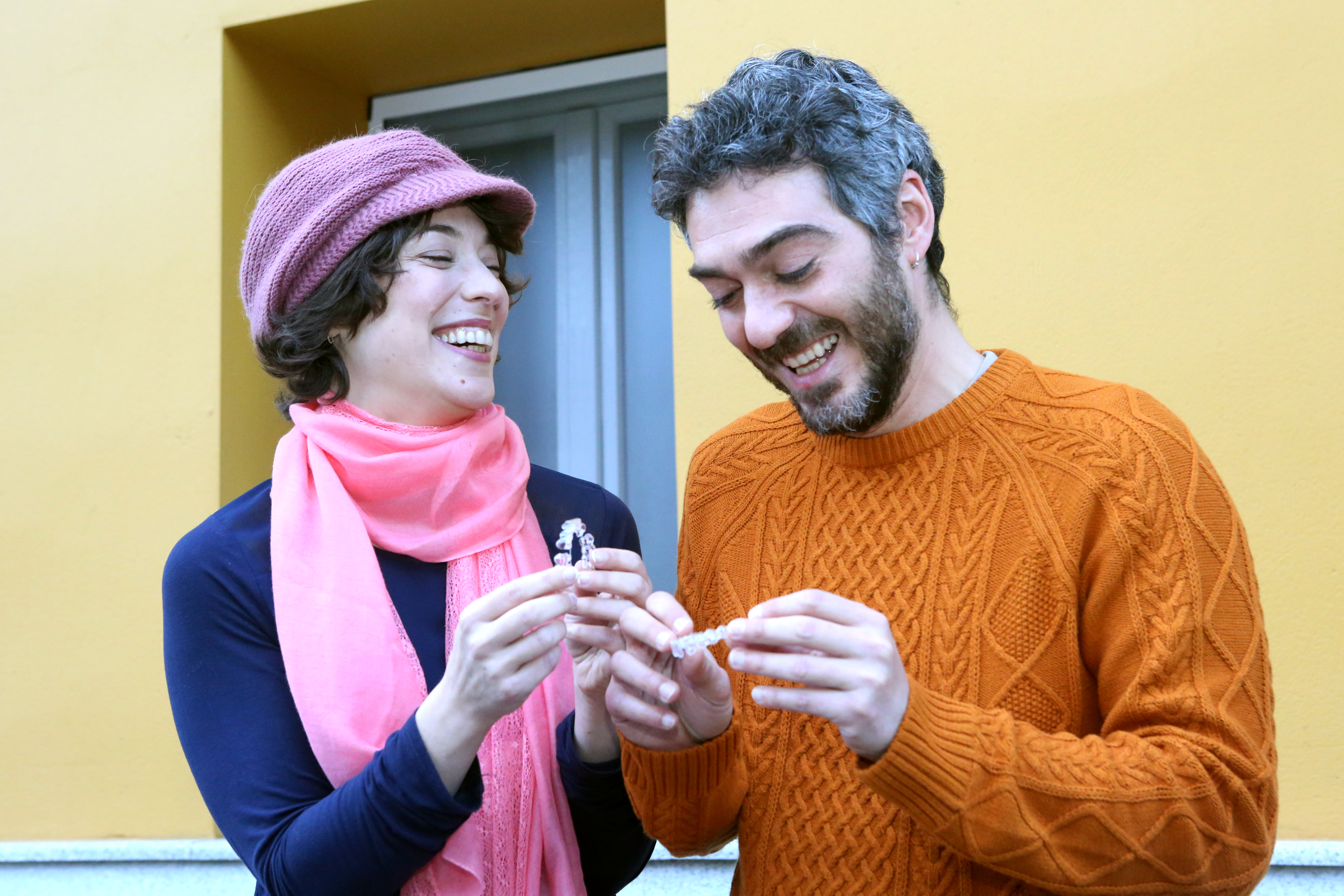Pareja sonriendo con ortodoncia invisible en las manos